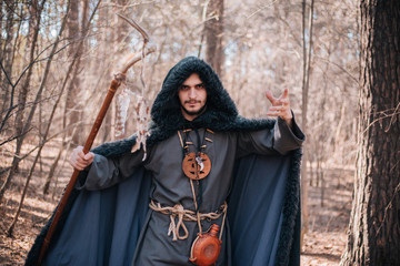 A man with a beard and a mustache in a robe and coat with a staff in his hand. A magician, a shaman...