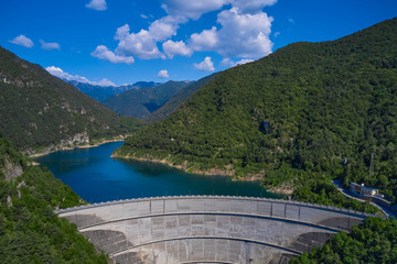 Obraz na płótnie Canvas Aerial view, dam of Diga di Ponte Cola -Valvestino, Lake Valvestino, Italy. Beautiful lake between the mountains. Cumulus clouds, blue sky