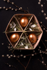 Easter eggs in a box with hay on a black background. vertical image