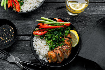 Teriyaki chicken fillet, fresh cucumber, red bell pepper, stew cabbage and basmati rice. Couple traditional Asian Buddha bowls. Top view, directly above shot.