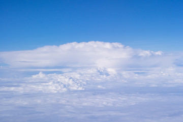Beautiful view from airplane window above the clouds. Bright blue sky and white clouds. Skyline background with copy space.