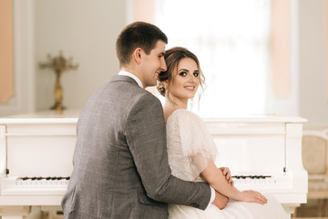 Beautiful elegant couple of newlyweds in love in a luxurious interior near the piano