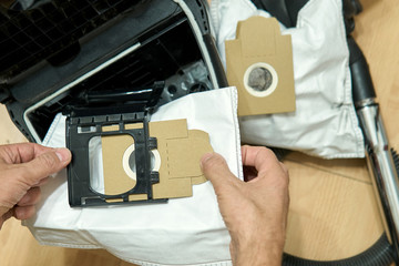 Male hands insert a new dust bag in vacuum cleaner during the dust bags replacement