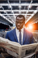 Businessman reading newspaper at subway station