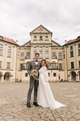 Beautiful elegant couple of newlyweds in love on the background of an old building and paving stones, European wedding