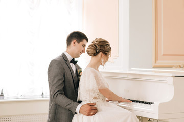 Beautiful elegant couple of newlyweds in love in a luxurious interior near the piano