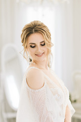 Naklejka premium Portrait of a beautiful young bride in a bright room in a romantic atmosphere. Close-up of wedding makeup and hairstyle