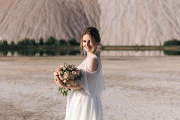 Fototapeta na wymiar Beautiful elegant bride on the background of salt sand quarries