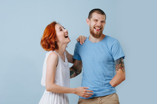 Happy Couple At Home Laughing Out Loud Over Blue Background.