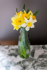 Bouquet yellow narcissus, red cardamon and many flowers in a glass vase 