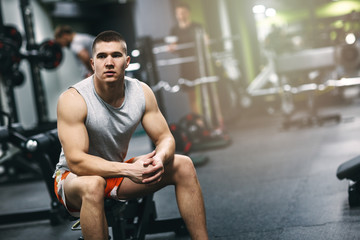 Fototapeta na wymiar Portrait of fitness man in gym sitting on bench