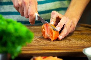 Woman hands cut tomato