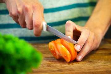 Young woman cuts the tomato with a knife