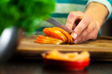 Female hands cut tomato into slices