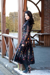 Beautiful woman with smile in dress near wooden handrail