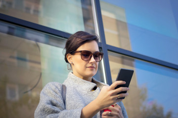 Beautiful businesswoman texting on the phone outdoors.