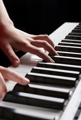 Closeup view of the child hands playing on electronic synthesizer piano keys. Vertical photo ready...