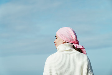 Close up photo of back view of young woman with cancer looking to left on the coast