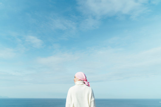 Back View Of Young Woman With Cancer Looking To Left On The Coast