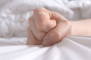 Unrecognizable depressed woman after domestic violence. Woman's fists clenched in fear, crumpled...