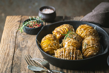 Baked hasselback potatoes with cheese, garlic and greens