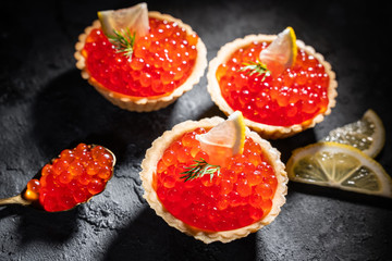 Tartlets with red caviar served on a black background. Gourmet seafood