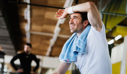 Sweaty after great work out. Handsome young men in sportswear whipping sweat with towel