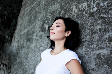 portrait of young pretty woman posing against the sreet grey wall/ Lady wearing white dress