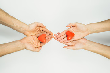 Female and male hands hold heart figures in palms on white background with copy space. Concept of charity, couples , relationships, love. St. Valentine's day concept