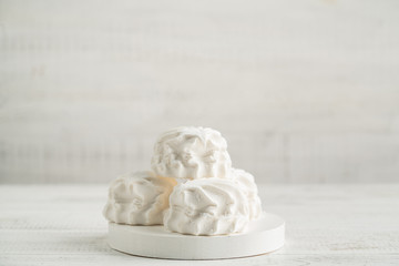 Marshmallow dessert in icing sugar on a light wooden background on a white board.