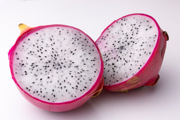 Top down view of two halves of white-fleshed Pitaya or Dragon fruit showing the white pulp with black seed insides on a light surface background