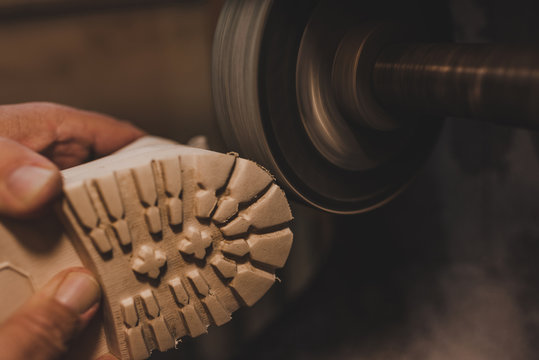 cropped view of cobbler polishing shoe sole on grinding machine