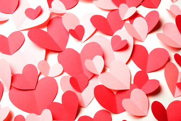 Bunch of cut out of pink and red paper hearts on white background closeup.