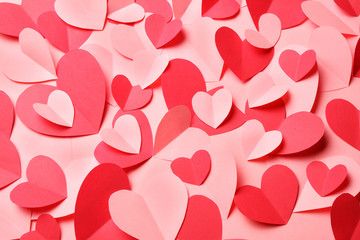 Bunch of cut out of pink and red paper hearts on pink background