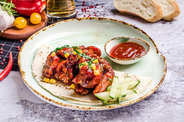 Closeup Homemade Buffalo chicken wings and chili pepper sauce, vegetables at a table background.