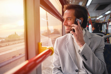 Cheerful young guy driving in a tram, having a pleasant phone talk