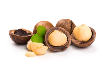 Macadamia nut with pieces and green leaves isolated on a white background