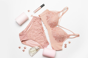 Romantic composition with female pink underwear, candle, lip gloss, perfume and stars decor on a gray background. Valentines day concept