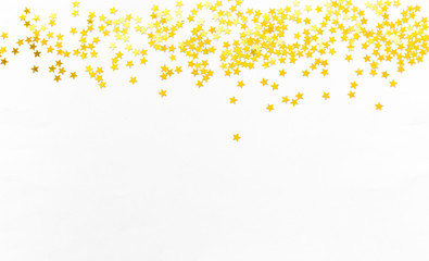 Gold confetti and stars and sparkles on a light background. Top view, flat lay. Copy text. Bright and festive background. For Christmas, New Year, Mother's Day.