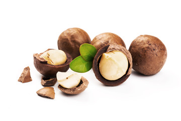 Macadamia nut with pieces and green leaves isolated on a white background