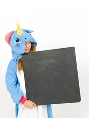 pretty blonde girl with cozy blue unicorn costume with blackboard is posing in the studio in front of white wall and is happy
