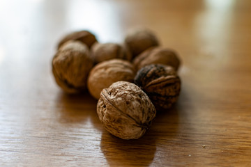  Solid and embossed brown-shelled walnuts lie on a wooden table, illuminated by the harsh sunlight