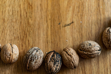  Solid and embossed brown-shelled walnuts lie on a wooden table, illuminated by the harsh sunlight