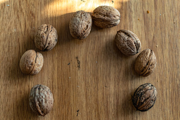  Solid and embossed brown-shelled walnuts lie on a wooden table, illuminated by the harsh sunlight