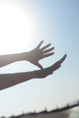 Young woman's hands reaching out towards the sky