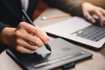 the abstract image of the designer using a graphics tablet and laptop computer in the office. the concept of designing, computer, digital and workspace.