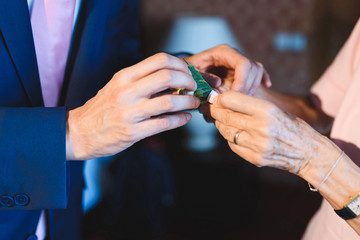 mother helping groom with boutonniere