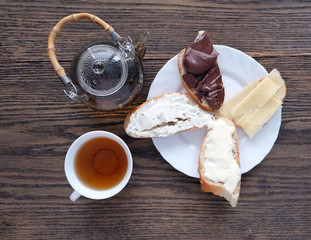green tea in a cup and teapot, a plate with sandwiches