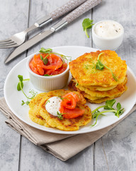 Fried potato pancakes with salmon and sour cream, fritter, roesti, golden crispy crust. Traditional...