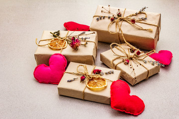 Zero waste gift concept. Valentine Day or Birthday eco friendly packaging. Festive boxes in craft paper with different organic decorations. Stone concrete background